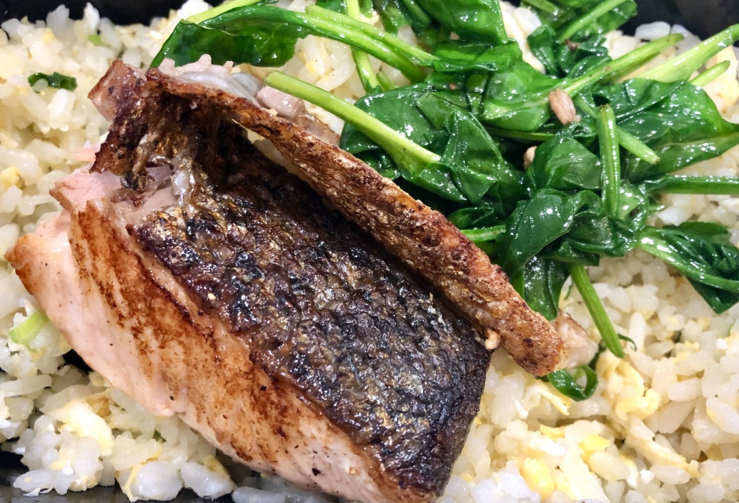 Pan-seared salmon and sautéed spinach on a bed of egg fried rice.